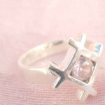 A web holding a pinky rhinestone design,designer inspired 925. sterling silver pendant
