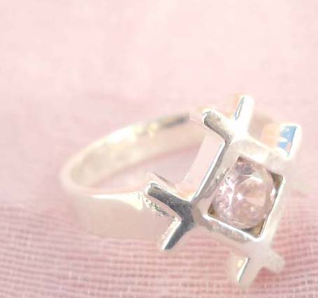 A web holding a pinky rhinestone design,designer inspired 925. sterling silver pendant